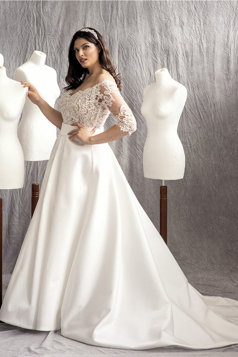 Abito da sposa curvy HAUDREY in pizzo e seta, modella tra manichini bianchi.
