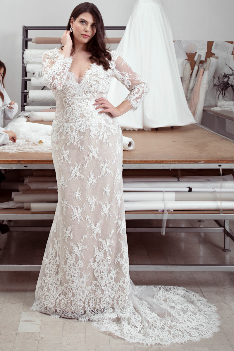Abito da sposa curvy Ophelia in pizzo bianco, maniche lunghe, scollo a V, modello in atelier sartoriale.