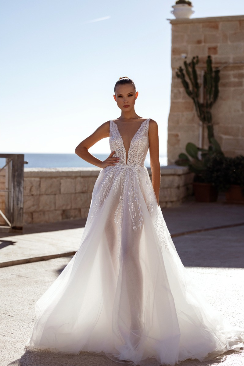Abito da sposa DALIA - MADIONI in pizzo e tulle, scollatura profonda, sfondo mare e cielo.