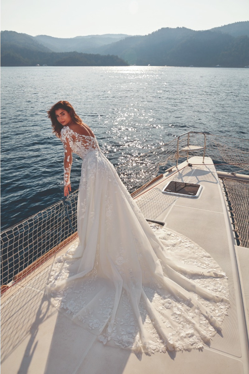 Abito da sposa UMA - EDDY K in pizzo su yacht, sfondo mare e montagne.