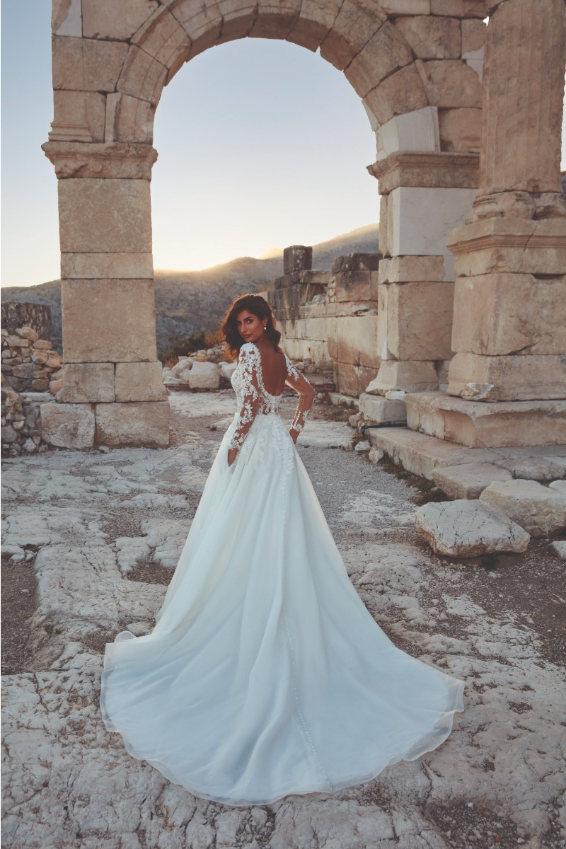 Abito da sposa Ireland Eddy K con dettagli in pizzo, sfondo di rovine antiche al tramonto.
