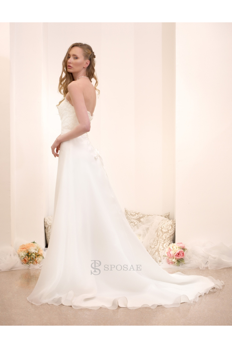 Abito da sposa elegante con strascico, modello senza spalline, ambientato in uno showroom con decorazioni floreali.