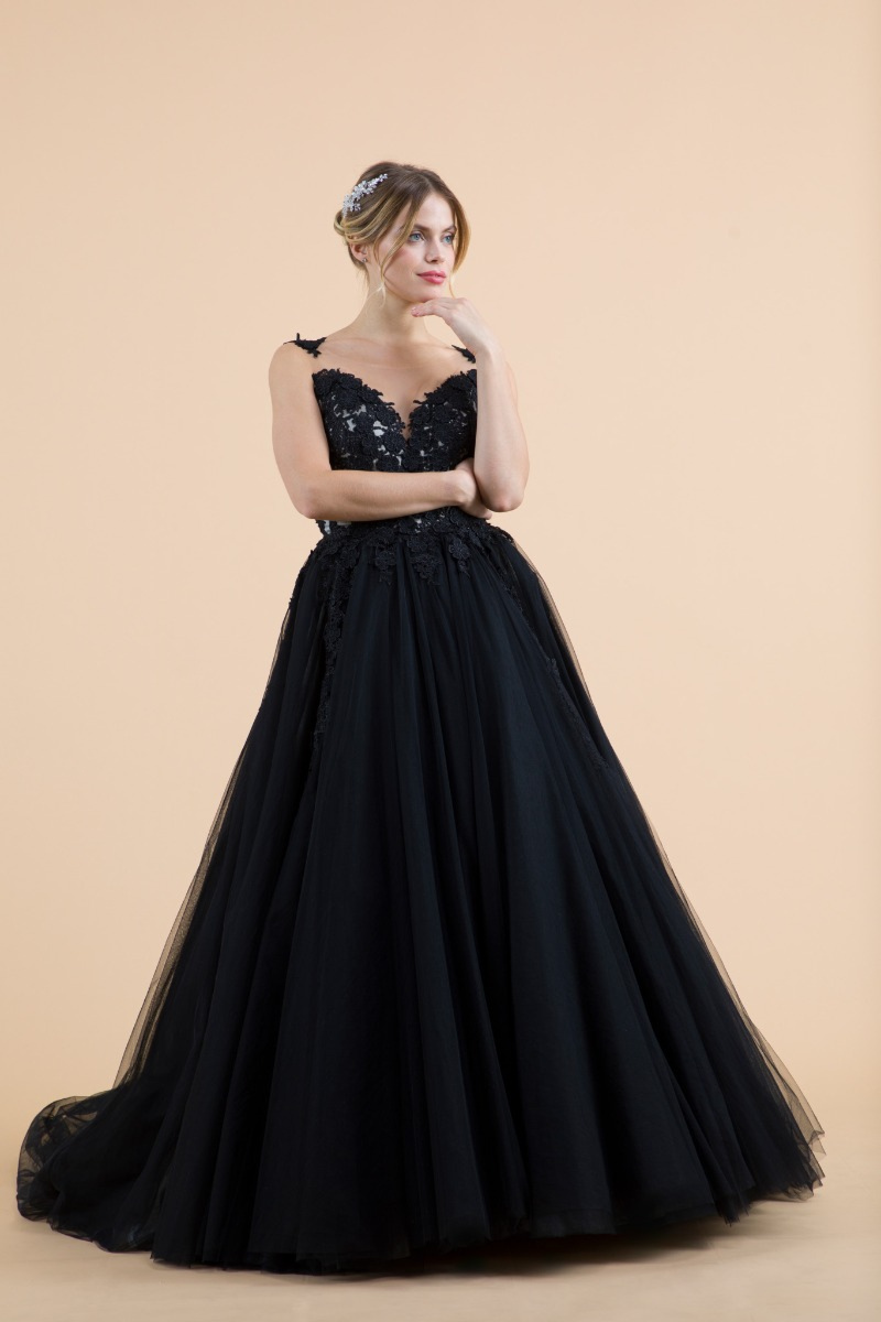 Abito da sposa Dulcamara nero con dettagli in pizzo, sfondo beige.
