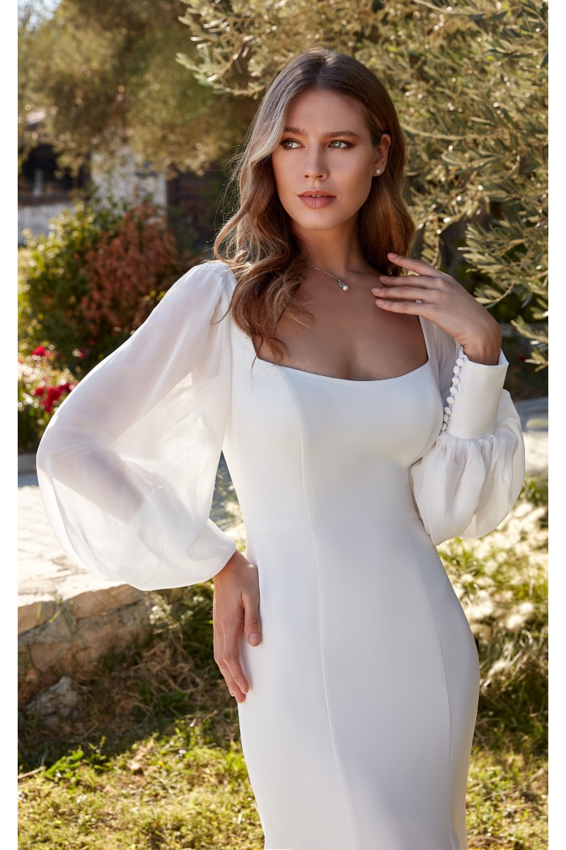Abito da sposa Gretchen Linea Eddy K con maniche a sbuffo in un giardino soleggiato.