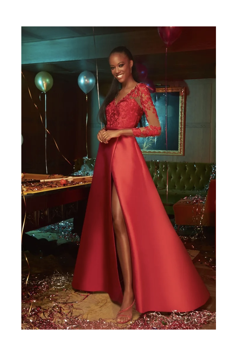Abito rosso elegante con dettagli in pizzo e spacco alto, collezione Pronovias, ambientazione festosa.