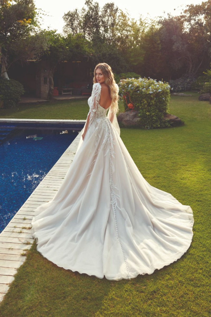 Abito da sposa Eddy K Palmer con strascico lungo, ambientato in giardino vicino a piscina.