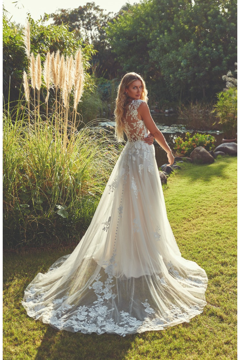 Abito da sposa FINLEY di Eddy K con dettagli in pizzo, sfondo naturale con piante e stagno.