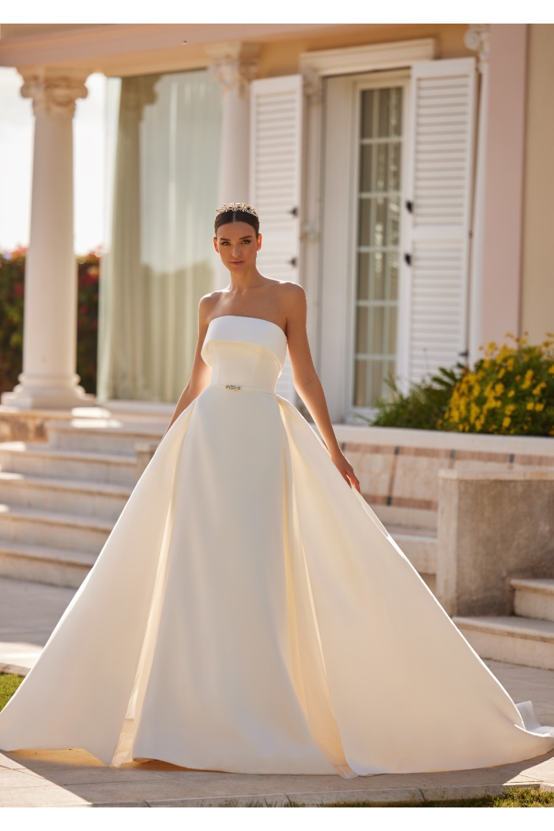 Abito da sposa ELEONOR di St. Patrick, elegante e senza spalline, ambientato in un giardino con colonne classiche.