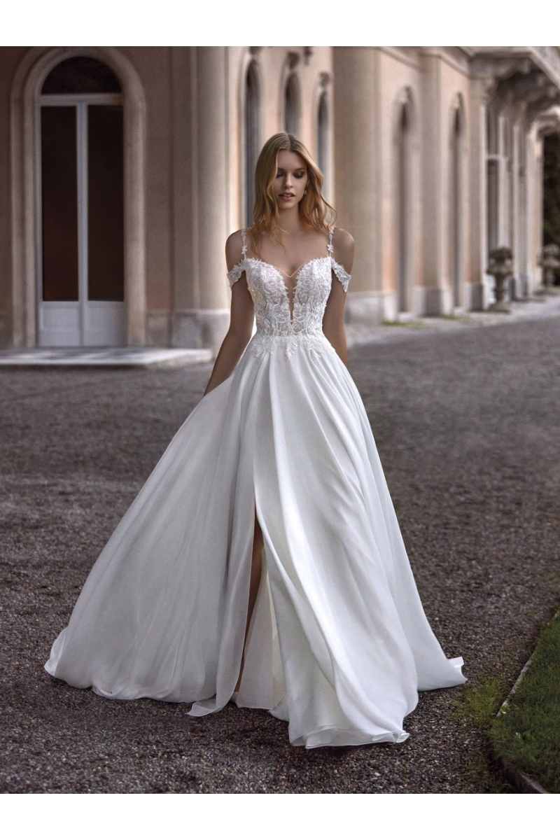 Abito da sposa ELOMA di Nicole Milano, elegante con corpetto ricamato e gonna fluida, ambientato in un contesto architetto...
