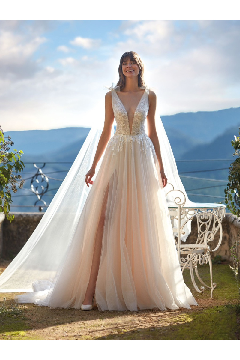Abito da sposa EMSLEY con scollo a V e spacco, ambientato in un giardino panoramico.