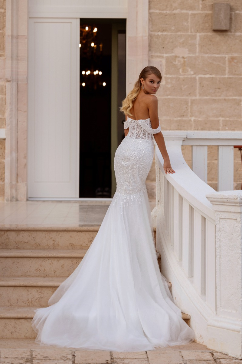 Abito da sposa GARDENIA - MADIONI, elegante con strascico, indossato su scala esterna.