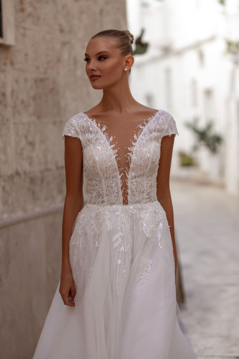 Abito da sposa HIBISCUS di MADIONI con dettagli in pizzo e scollo profondo, indossato da modella in strada.