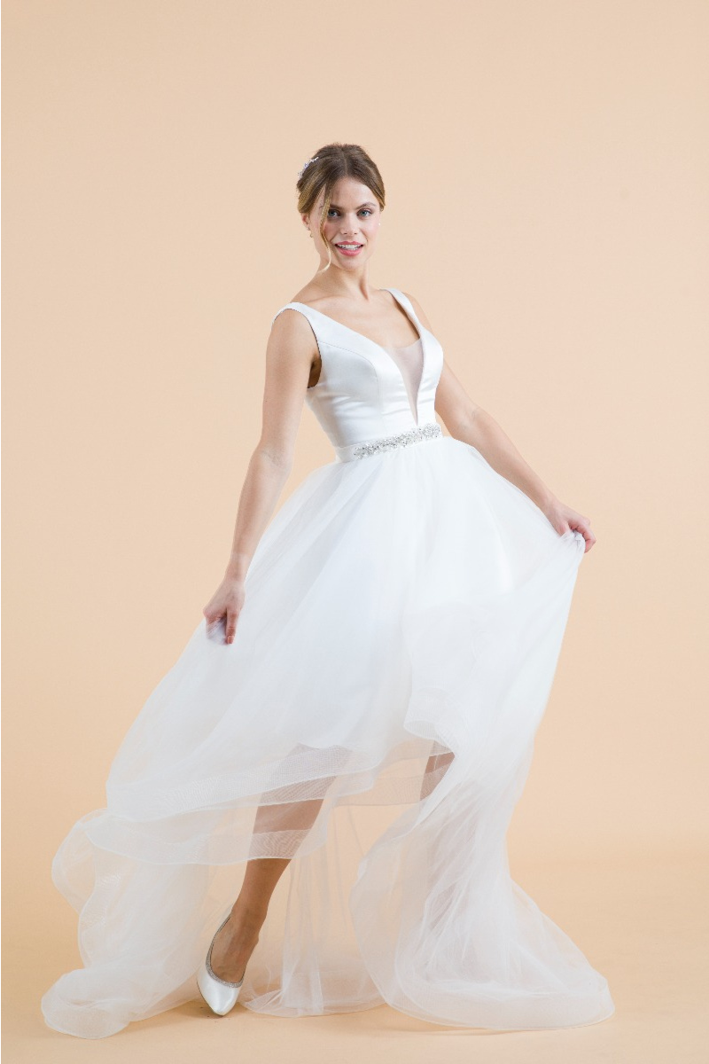 Modella con abito da sposa ciclamino, gonna vaporosa, sfondo beige.