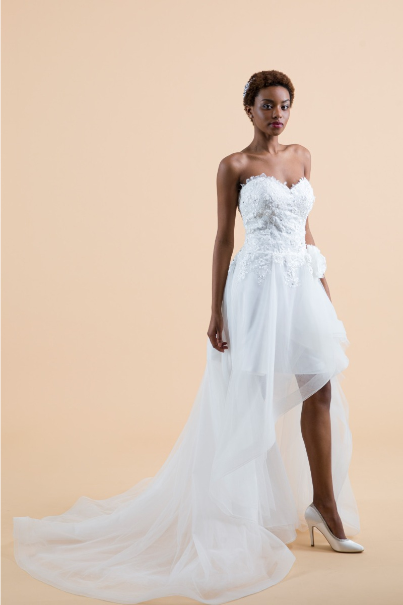 Abito da sposa passiflora con corpetto ricamato e gonna asimmetrica, sfondo neutro.