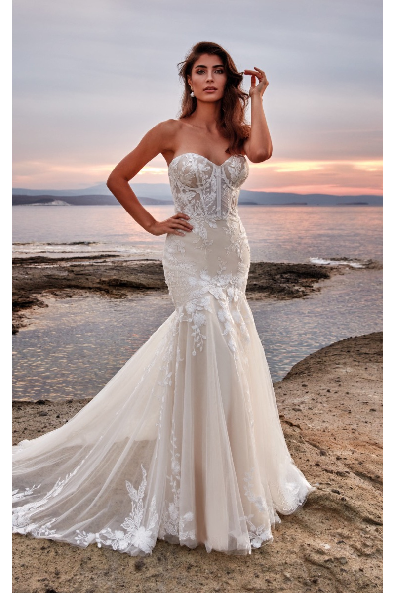 Abito da sposa Isabella di Eddy K, elegante e romantico con dettagli in pizzo, sfondo al tramonto sul mare.
