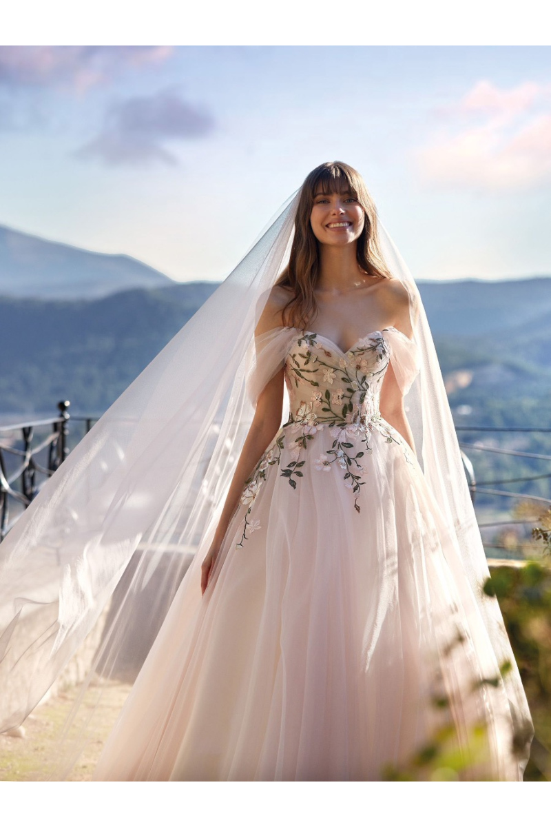 Abito da sposa JELENA di Nicole Colet con dettagli floreali, ambientato in un paesaggio montano.