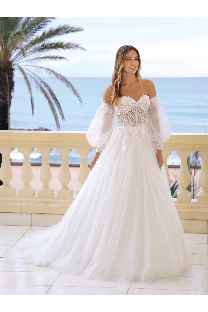 Abito da sposa Karalee Ladybird in pizzo con maniche a palloncino, sfondo mare e palme.