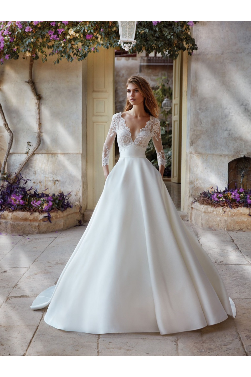 Abito da sposa KEZIA di Nicole Colet con corpetto in pizzo e gonna ampia, ambientazione romantica all'aperto.