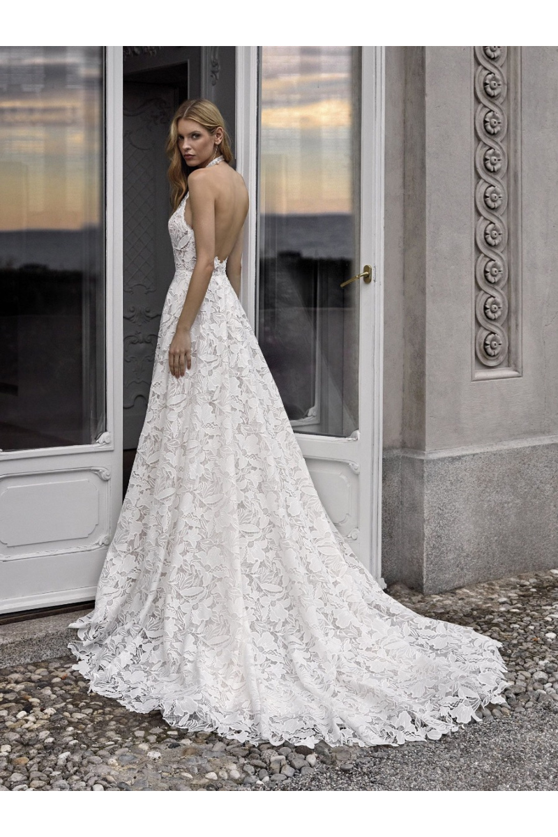 Abito da sposa Nicole Milano KIA in pizzo floreale, schiena scoperta, ambientazione elegante.