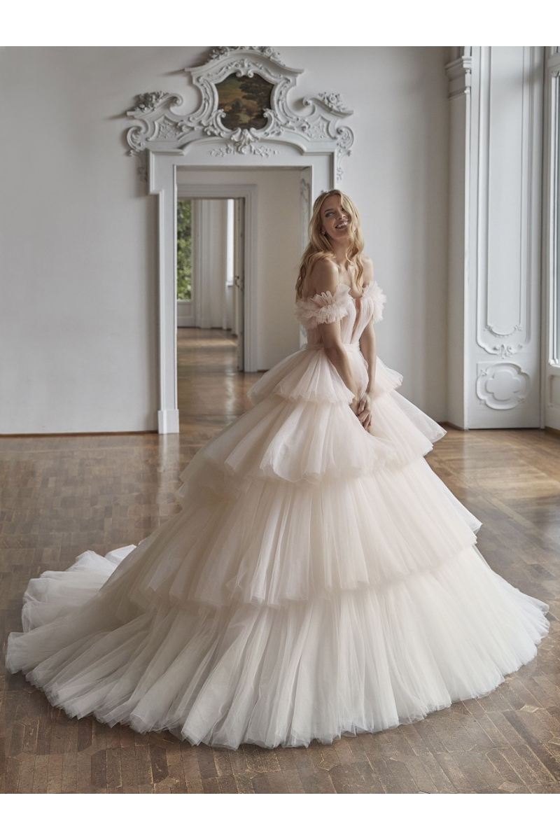 Abito da sposa a balze in tulle KIENA in una sala elegante, perfetto per un matrimonio da sogno.