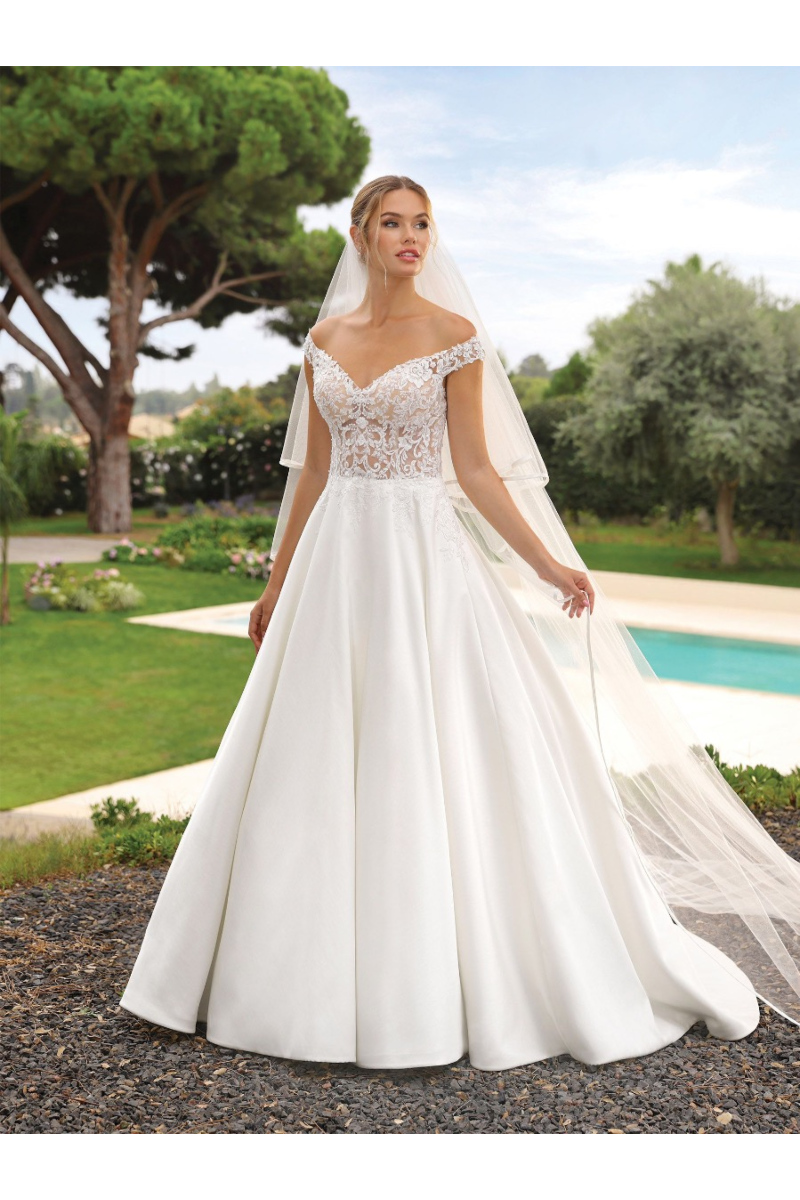 Abito da sposa Kunna Ladybird con corpetto in pizzo e gonna ampia, sfondo giardino.