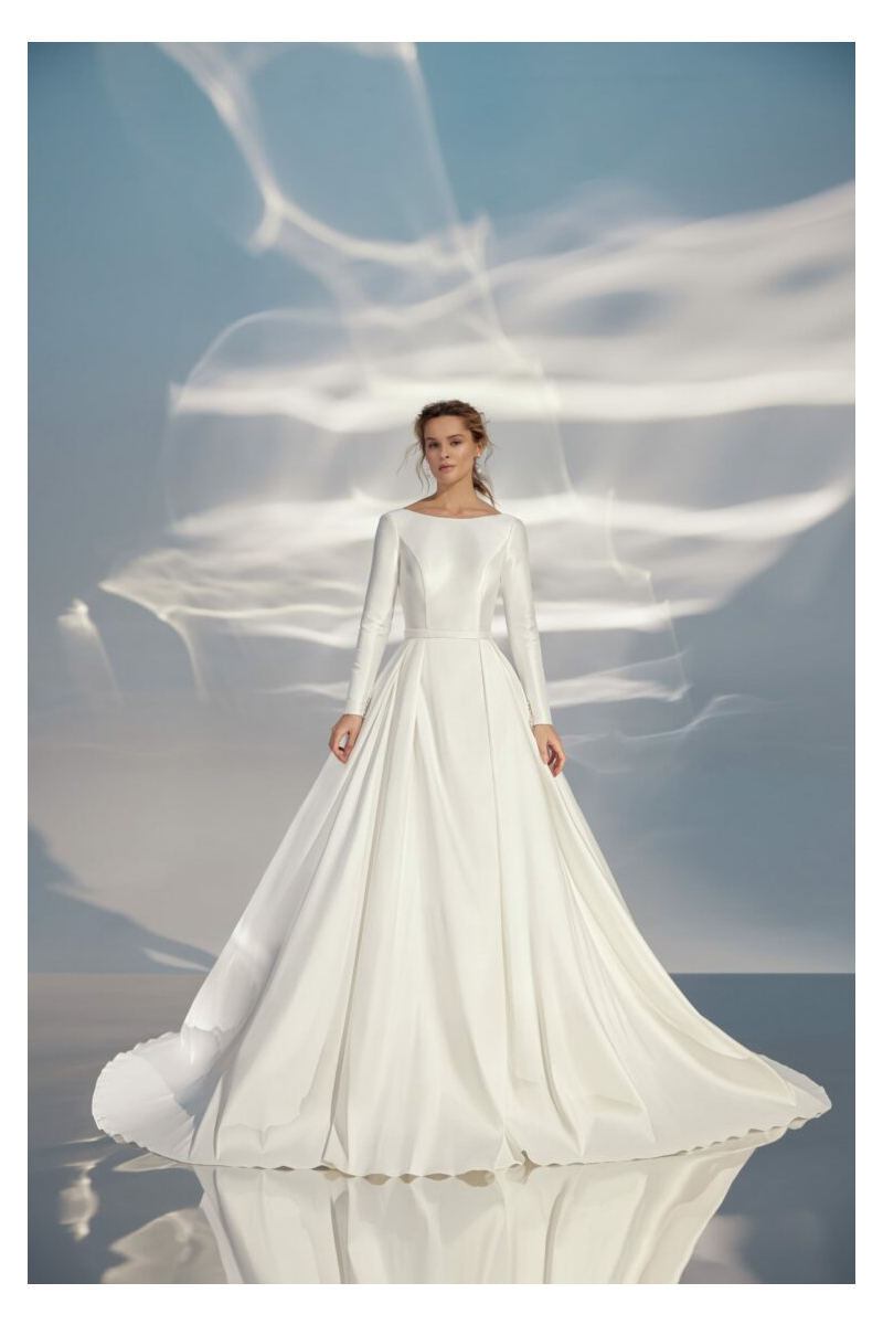 Abito da sposa L319 ARIAMO LIGHT, elegante e moderno, con maniche lunghe e gonna ampia su sfondo etereo.