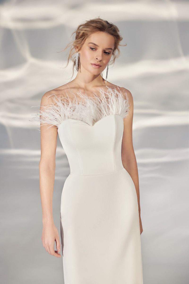 Abito da sposa elegante L331 ARIAMO LIGHT con dettagli piumati, sfondo sfumato.
