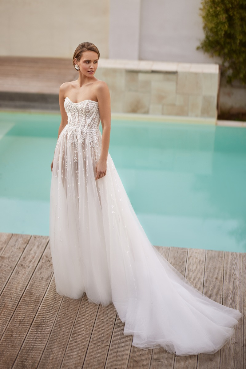 Abito da sposa LAZURITE di Mark Loren, design elegante con dettagli in pizzo, ambientato vicino a una piscina.