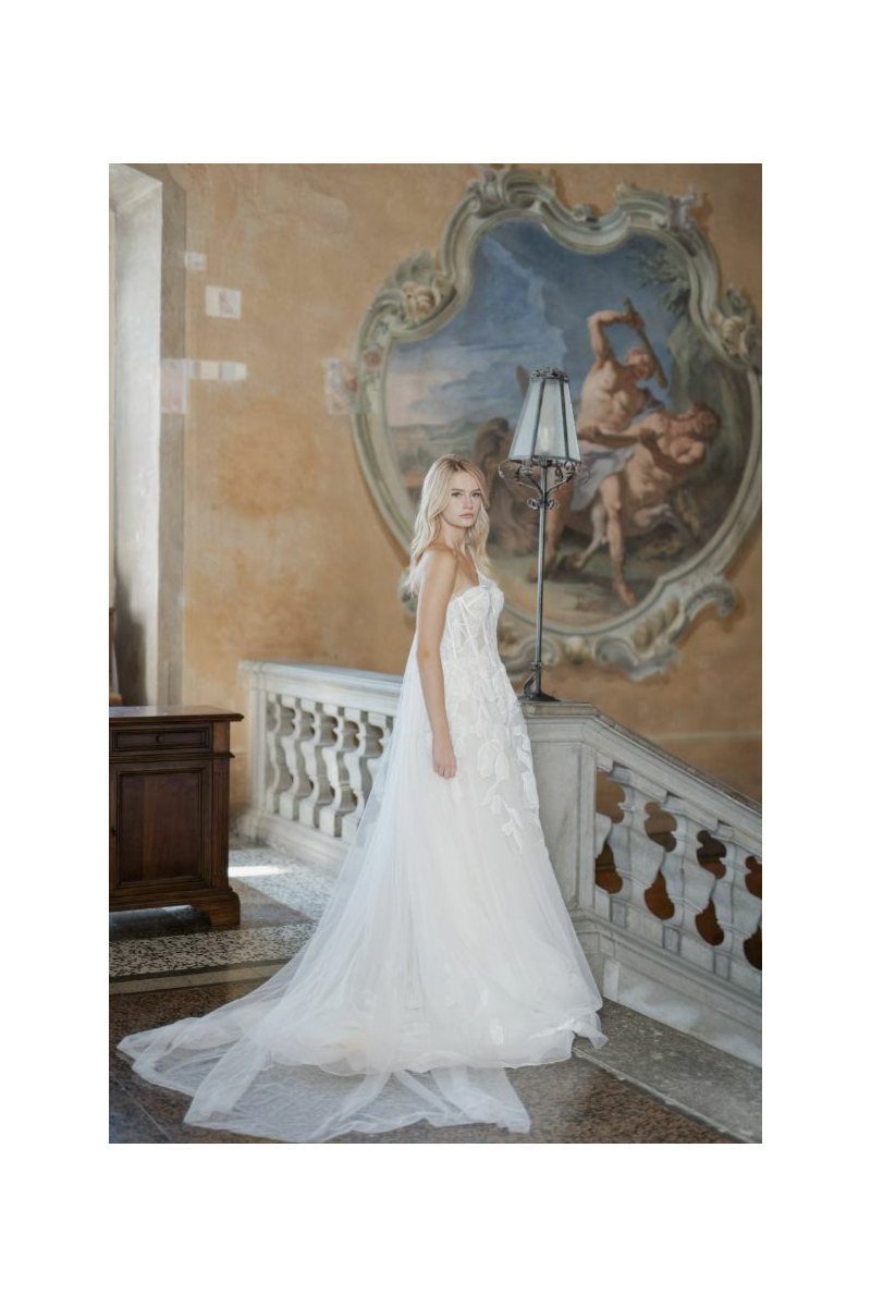 Abito da sposa HALE-BOPP Linea Sposae Atelier, donna in posa su scala con affresco.