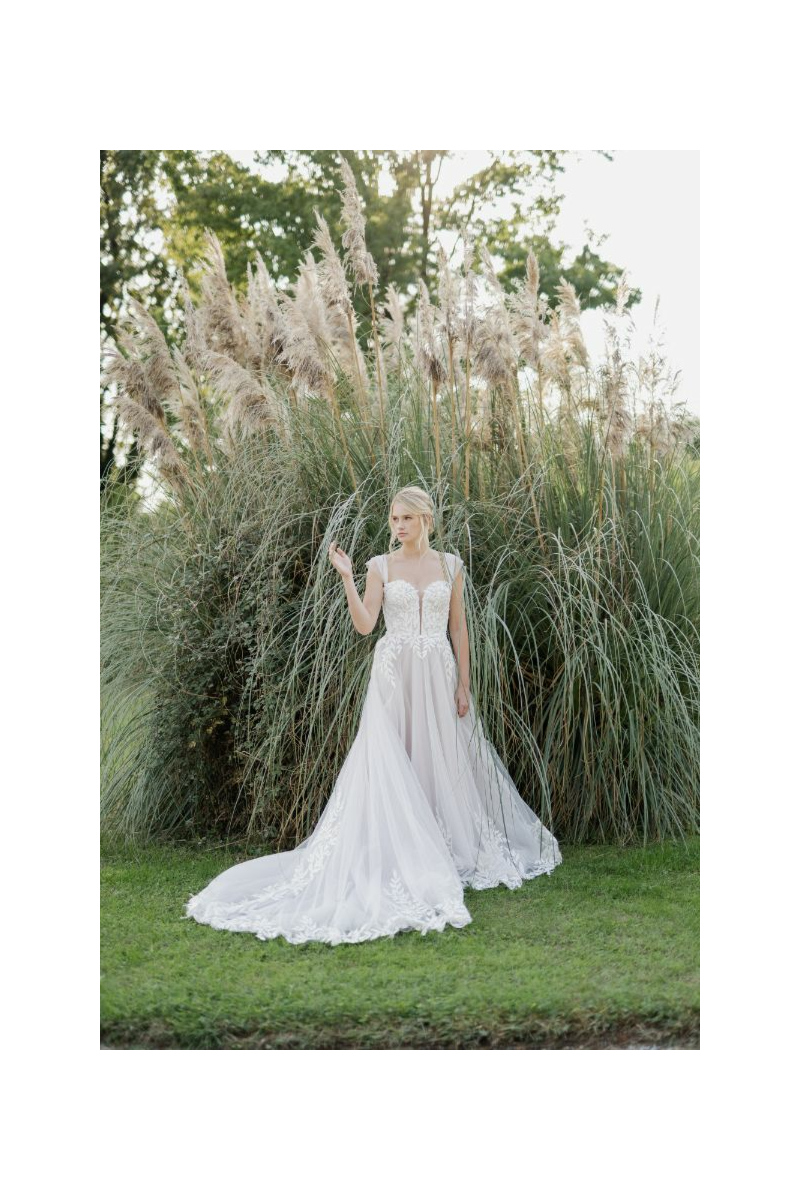 Abito da sposa OFELIA di Sposae Atelier, elegante e romantico, con dettagli in pizzo, ambientato in un giardino verde.