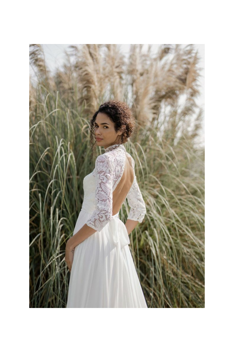 Abito da sposa in pizzo con schiena scoperta, Linea Sposae Atelier, ambientato in un paesaggio naturale.