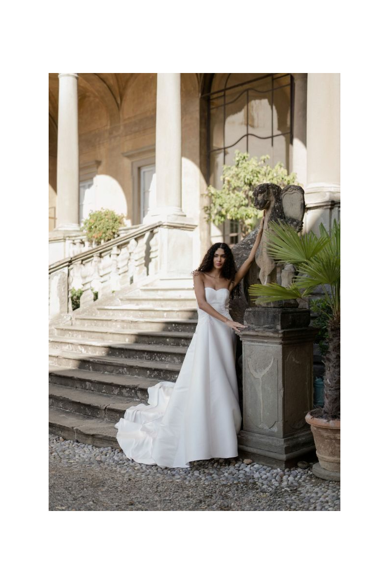 Abito da sposa Nettuno Linea Atelier Sposae, elegante design in ambientazione storica con scalinata e statua.