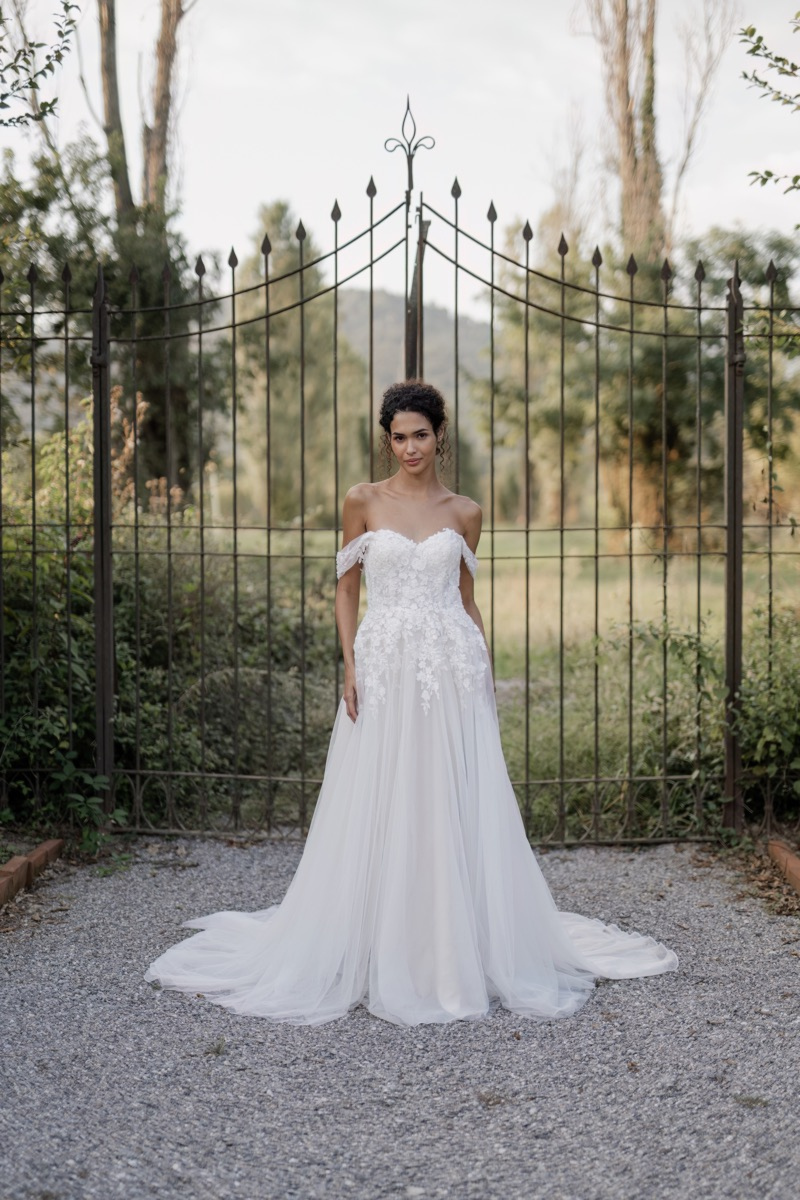 Abito da sposa Deneb Linea Sposae Atelier, stile romantico, sfondo giardino con cancello in ferro battuto.