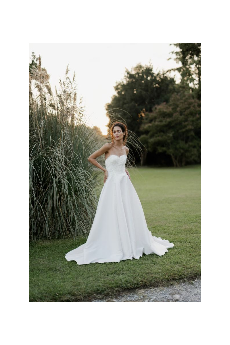 Abito da sposa elegante Capricorn di Sposae Atelier, modello senza spalline, ambientato in un giardino verde.