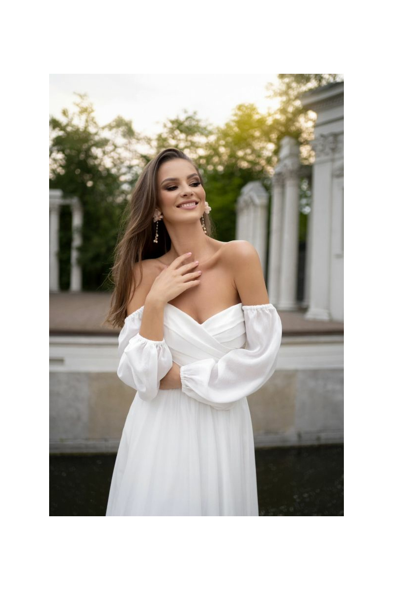 Abito da sera bianco POLA - DAMA con spalle scoperte, indossato all'aperto, sfondo architettonico elegante.