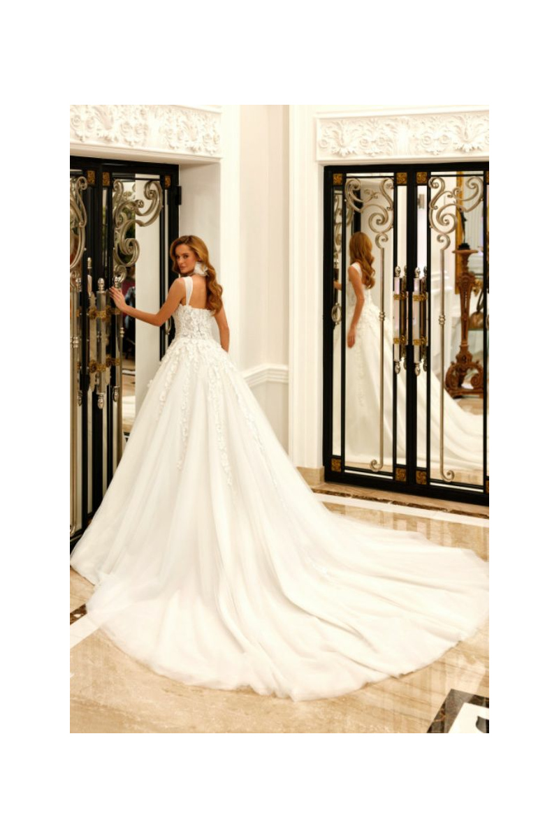 Abito da sposa ROSE di Mark Loren, elegante e lungo con dettagli floreali, indossato in un interno lussuoso.
