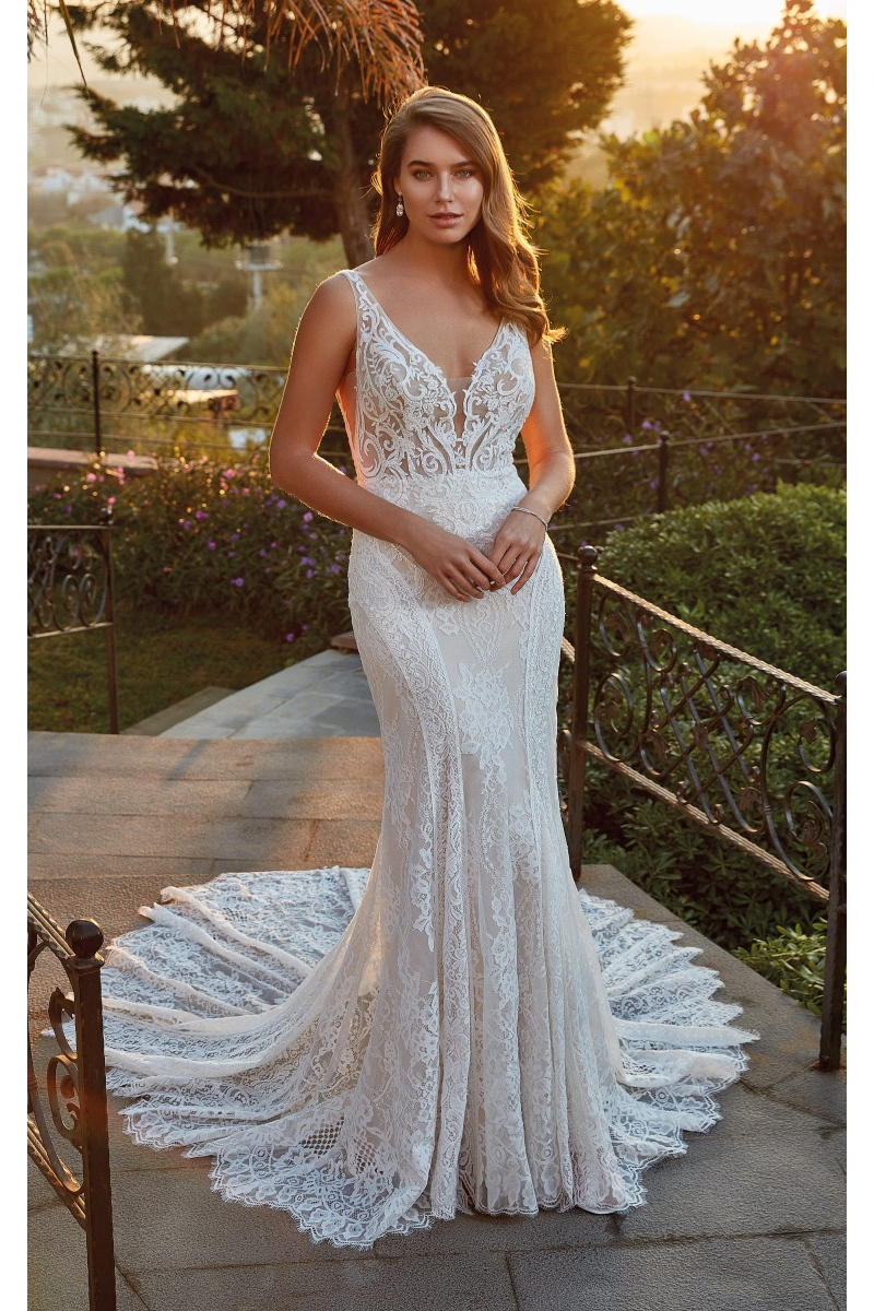 Abito da sposa Stacey di Eddy K in pizzo, scollatura profonda, sfondo giardino al tramonto.