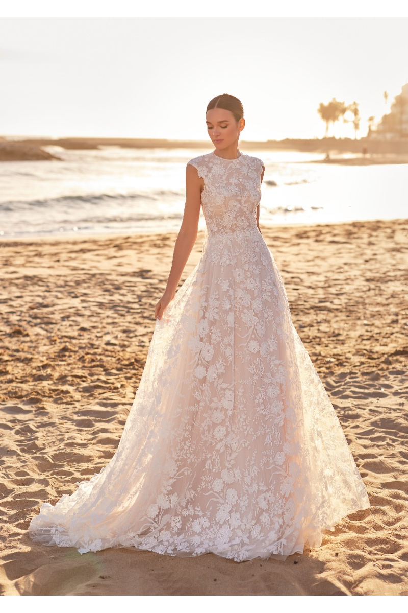 Abito da sposa TALULAH in pizzo floreale su spiaggia al tramonto.