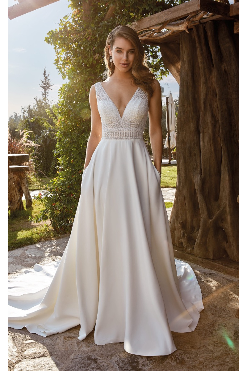 Abito da sposa Terry di Eddy K, scollo a V, tessuto fluido, ambientazione esterna naturale.