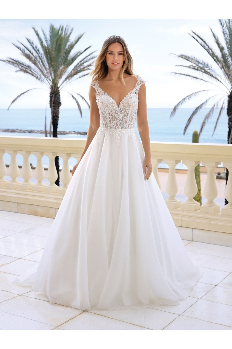 Abito da sposa Zain Ladybird in pizzo, scollo a cuore, sfondo mare e palme.
