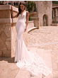 Abito da sposa NIREUS bianco con dettagli in pizzo, sfondo architettura mediterranea.