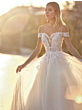 Abito da sposa Ingrid Linea San Patrick con dettagli in pizzo, scollo a cuore e maniche corte, sfondo solare.