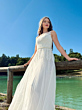 Abito da sposa IDA20 in pizzo bianco, sfondo naturale con lago e cielo azzurro. Saldi disponibili.