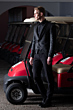 Abito da uomo elegante nero 22U152030C indossato, sfondo con golf cart rossi.