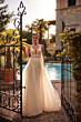Abito da sposa BEATRIX - DAMA con dettagli floreali, indossato in un giardino elegante con piscina.