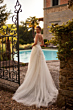 Abito da sposa BEATRIX - DAMA in giardino elegante, vicino a piscina e cancello in ferro battuto.