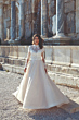 Abito da sposa Eliana di Eddy K con pizzo dettagliato, sfondo architettonico antico.