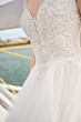 Abito da sposa Maggie Sottero Imena con dettagli in pizzo e perline su sfondo marino.