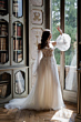 Abito da sposa romantico EVA in pizzo e tulle, maniche ampie, ambientato in una biblioteca elegante.