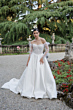 Abito da sposa AKOYA-Romantica by Sposae, design elegante in giardino fiorito, sfondo verde lussureggiante.